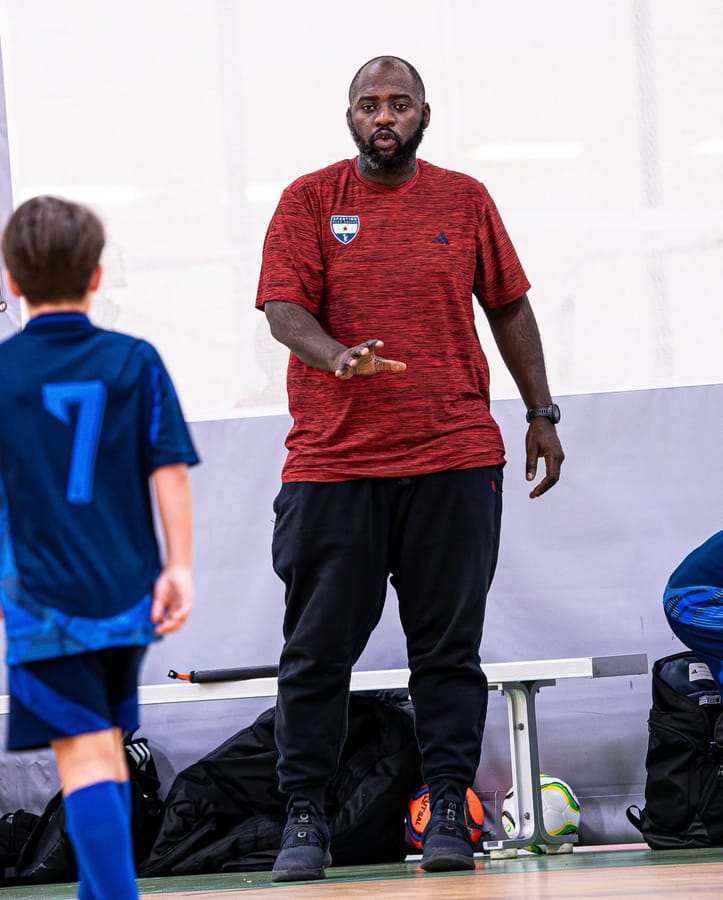 An SBV coach giving a player directions on a gym floor