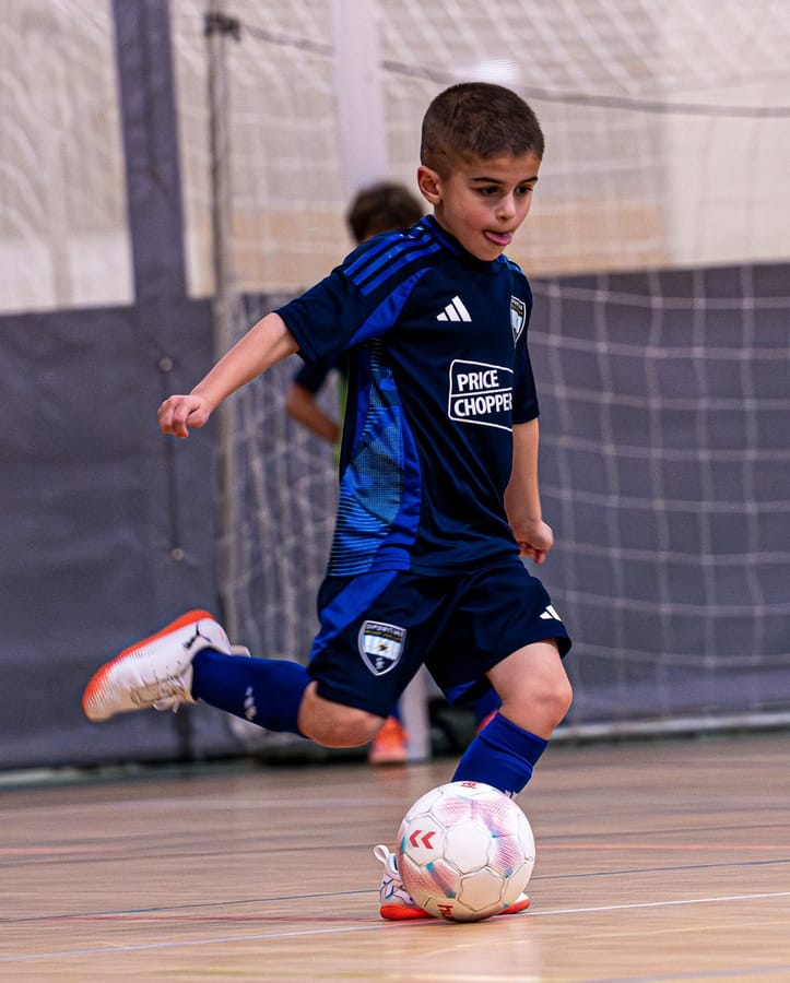 An SBV player in the navy kit striking the ball on a gym floor