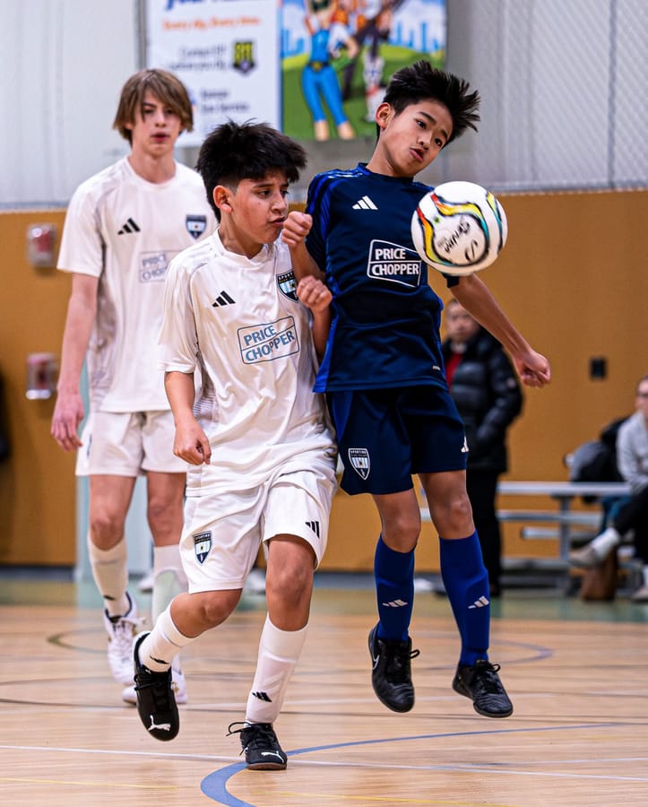 SBV players in navy and white going up for a header in a gym